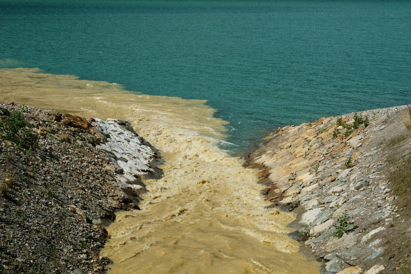 Eaux usées brunâtres se déversant dans une rivière bleue — photo d’illustration (banque d’images)