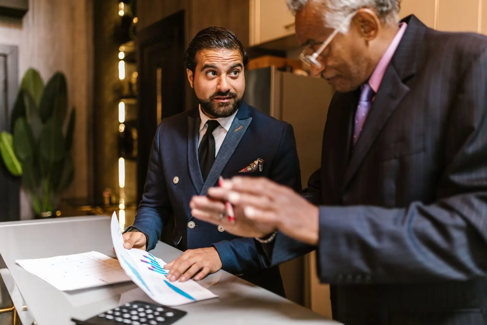 Deux professionnels en costume examinent des documents financiers et graphiques — photo d’illustration (banque d’images)