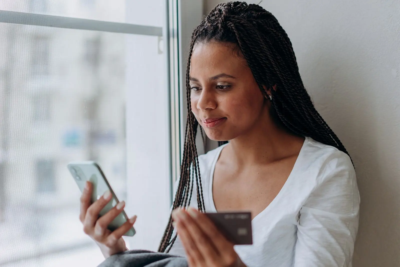 Jeune Sud-Africaine utilisant un smartphone et une carte bancaire — photo d’illustration (banque d’images)