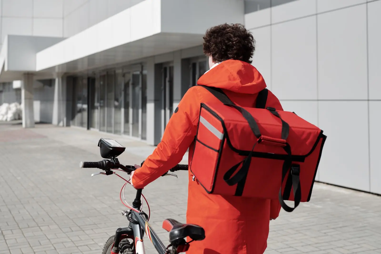 Coursier à vélo portant un sac isotherme de livraison — photo d’illustration (banque d’images)