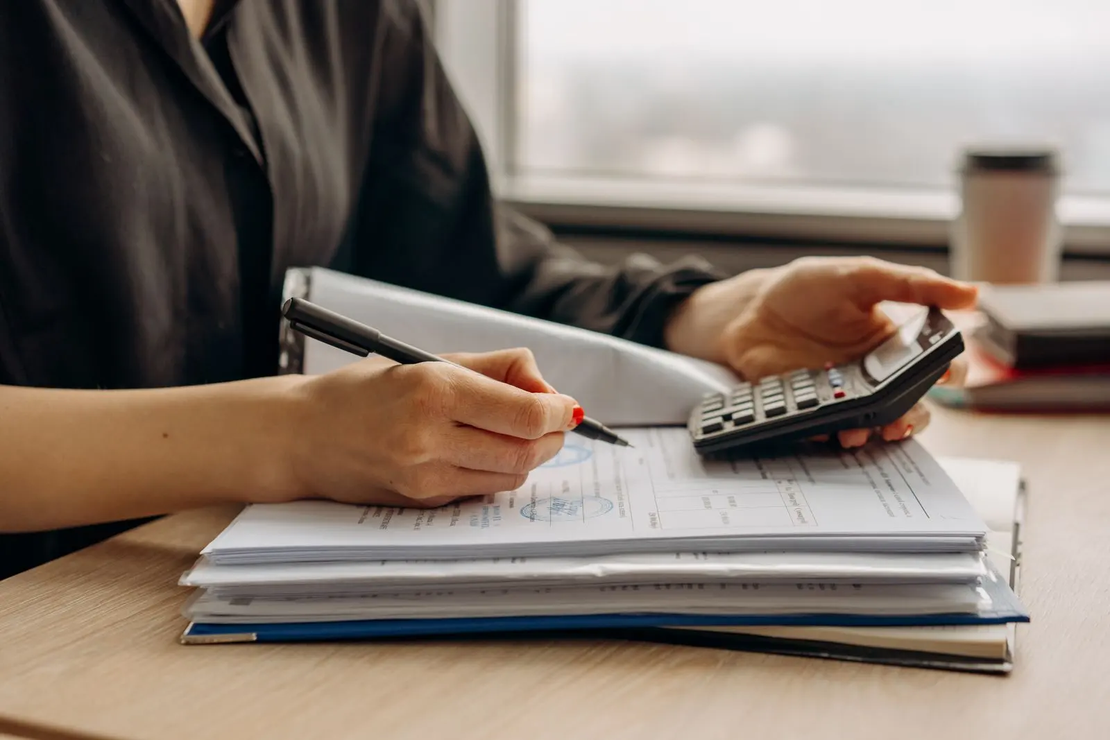 Personne calculant sur des documents financiers au bureau — photo d’illustration (banque d’images)