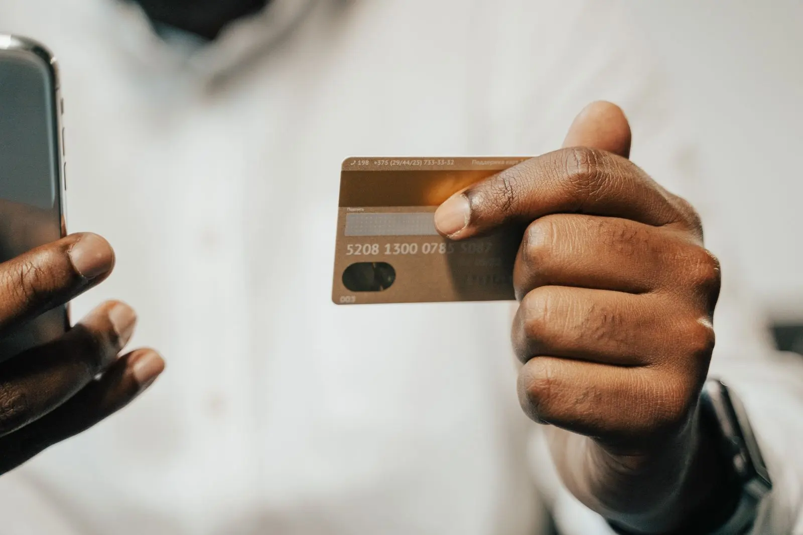 Main africaine utilisant une carte bancaire avec smartphone — photo d’illustration (banque d’images)