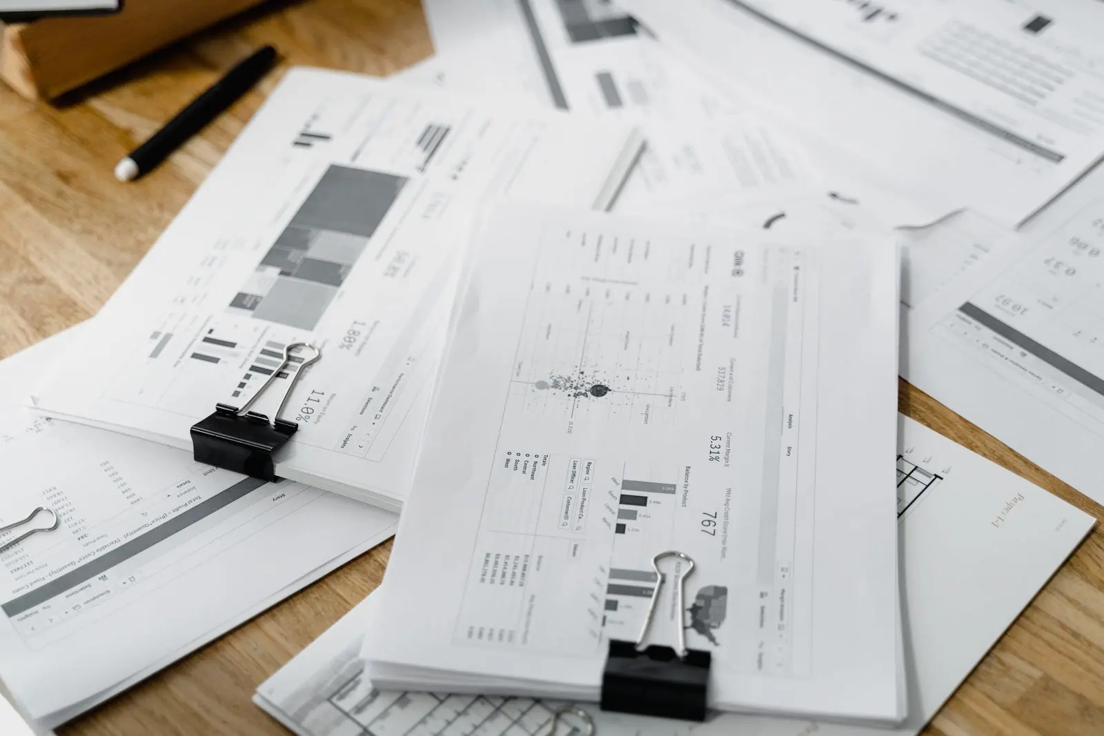 Rapports financiers et graphiques empilés sur un bureau — photo d’illustration (banque d’images)