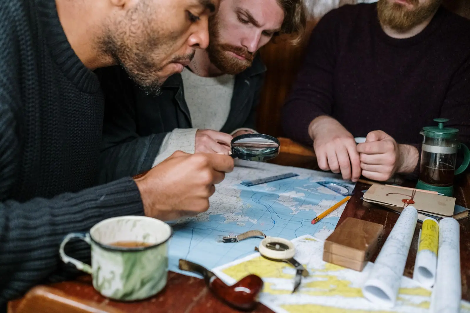 Des hommes examinent ensemble une carte avec une loupe — photo d’illustration (banque d’images)