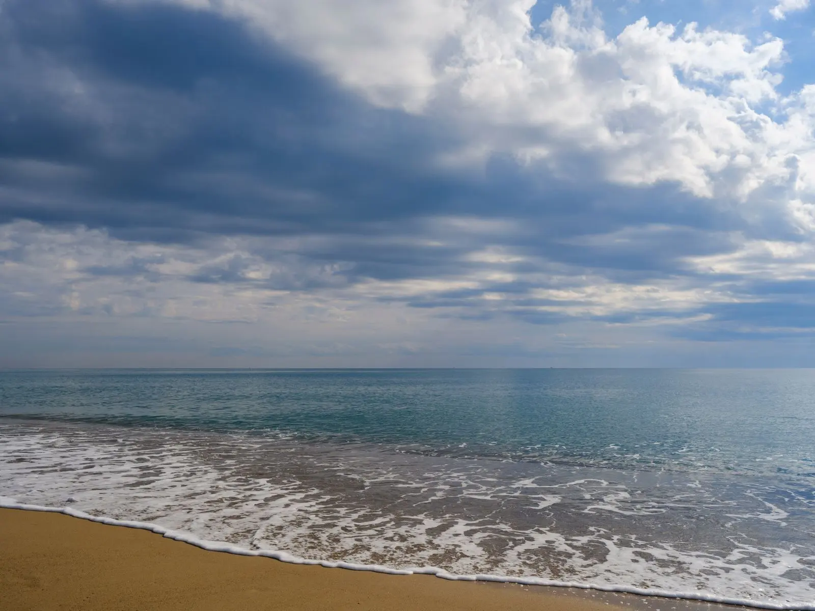 Plage sablonneuse tunisienne sous un ciel nuageux et chargé — photo d’illustration (banque d’images)