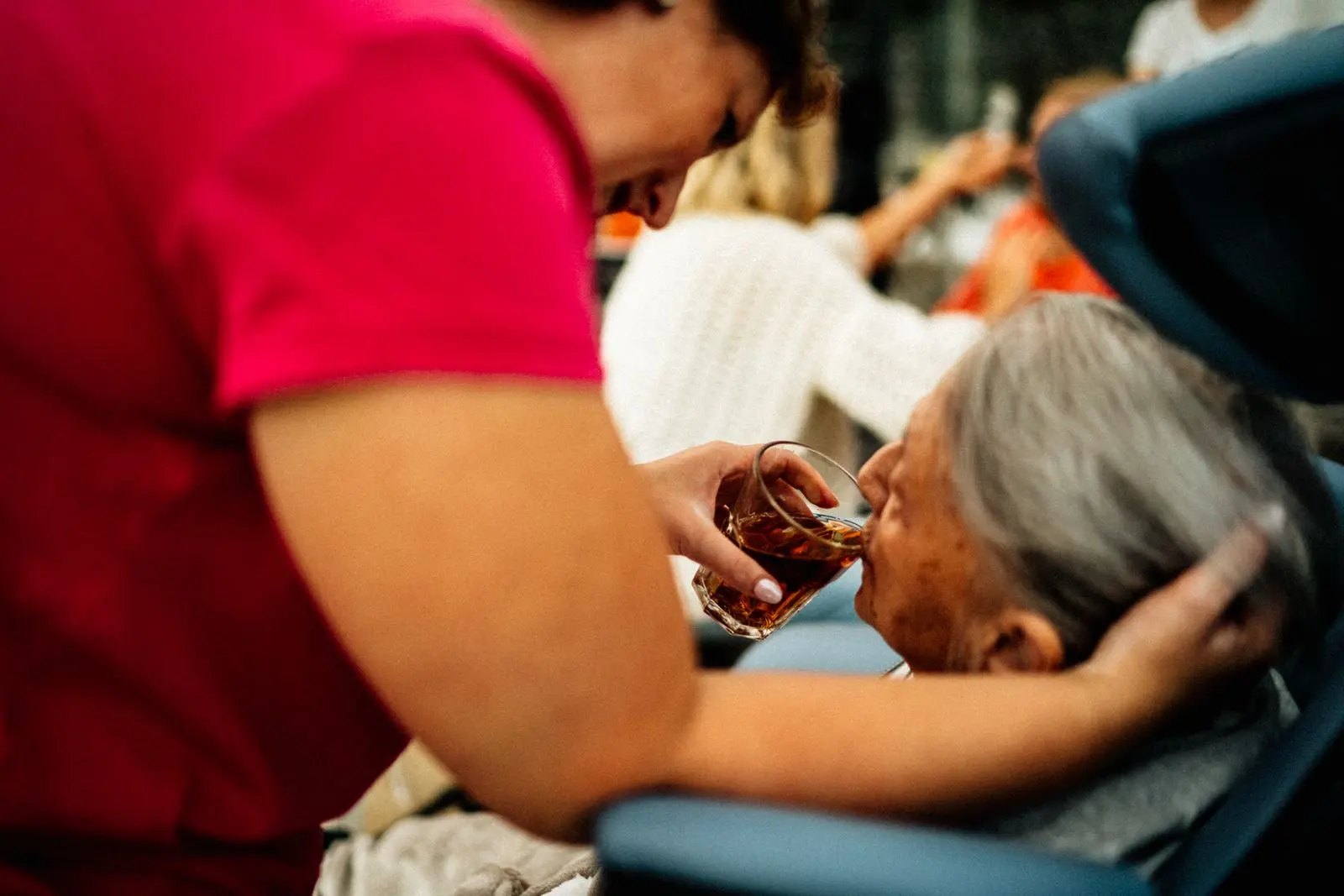 Aidante faisant boire une personne âgée à domicile — photo d’illustration (banque d’images)